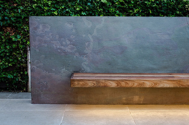 Natural stone veneer outdoor feature wall with wooden bench. 